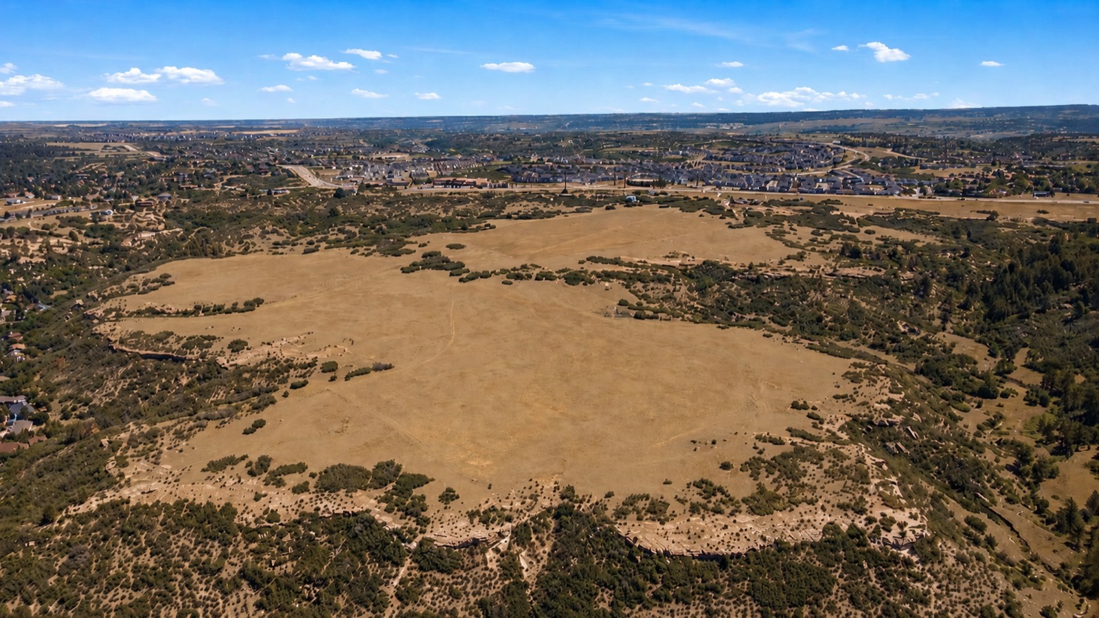 Aerial view of the open property with existing Castle Rock development beyond
